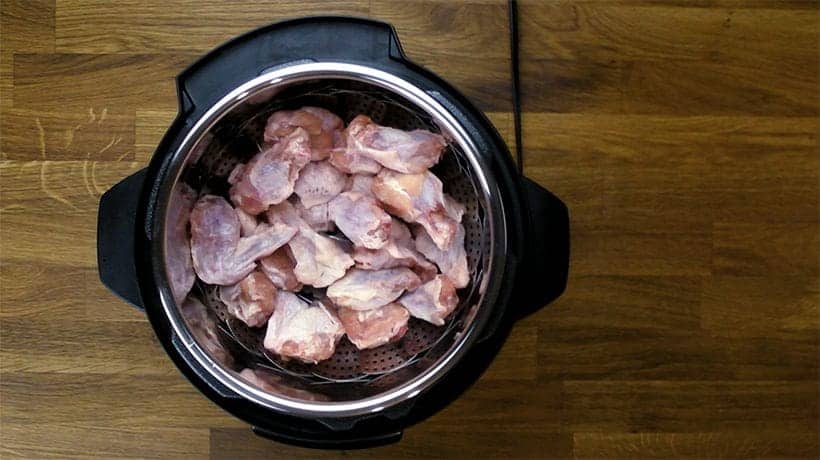 placing chicken wings in pressure cooker on a steamer basket